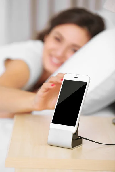 Красива молода жінка прокидається з мобільним будильником — стокове фото