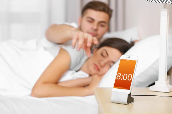 Šťastný pár probuzení s mobilní budík — Stock fotografie