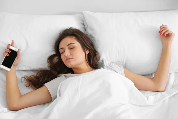 Mulher bonita acordando com despertador móvel — Fotografia de Stock