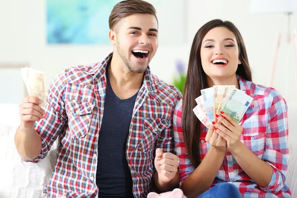 Boldog pár ül otthon, és pénzt a malac persely számolás — Stock Fotó