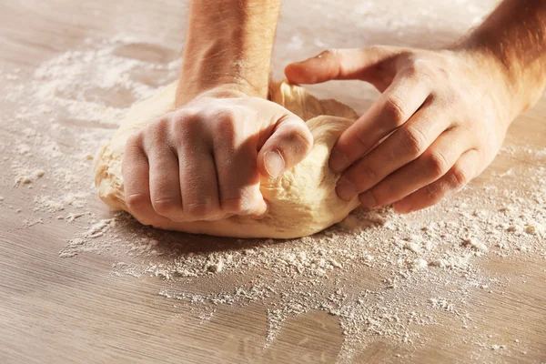 Ruce hnětení těsta na pizzu na dřevěný stůl, detail — Stock fotografie