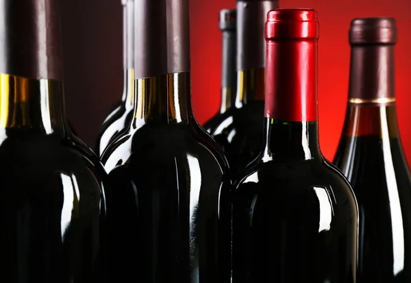 Weinflaschen auf rotem Hintergrund — Stockfoto