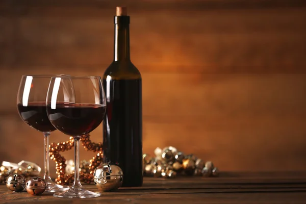 Red wine and Christmas ornaments on wooden table on wooden background — Stock Photo, Image