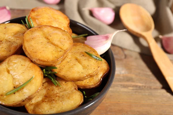 Läckra bakad potatis med rosmarin i skål på bordet på nära håll — Stockfoto