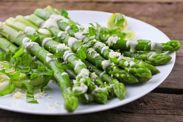 Apetyczny szparagi w sosie kwaśną śmietaną z cebulą i serem na biały talerz drewniany tle — Zdjęcie stockowe