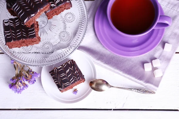 Serviert Tisch mit Schokoladenkuchen und einer Tasse Tee auf weißem Holzhintergrund — Stockfoto