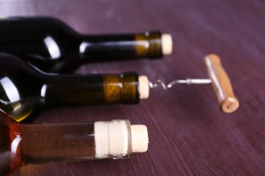 Üç şişe şarap ve tirbuşon mor ahşap zemin üzerine