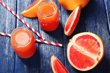 Greyfurt suyu şişeleri ve koyu mavi ahşap zemin üzerine taze meyve