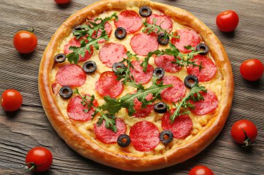 Ahşap arka plan domates lezzetli pizza salam ile süslenmiş