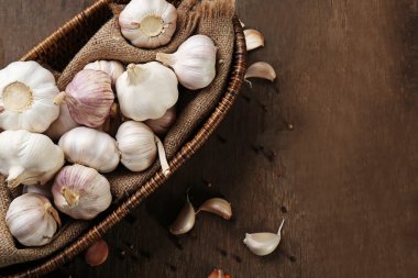 Ahşap arka plan üzerinde hasır kapta sarımsak