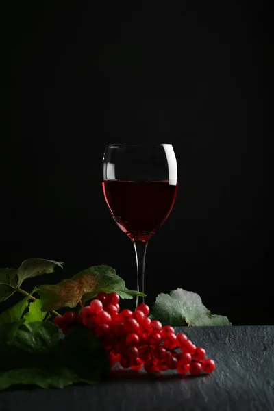 Бокал вина и красного винограда, на серо-черном фоне — стоковое фото
