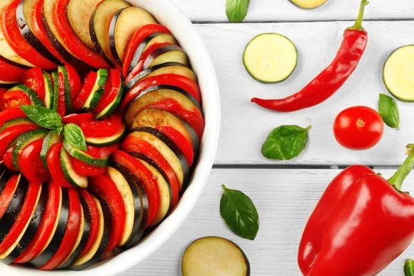 Ratatouille, plat de légumes cuits aux tomates, courgettes, aubergine avant cuisson dans une casserole, sur fond bois — Photo