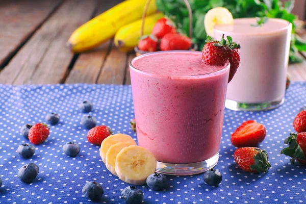 Glasses of fresh cold smoothie with fruit and berries, on blue tablecloth background — Stock Photo, Image