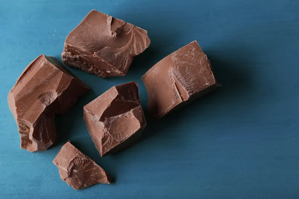 Piezas de chocolate con leche sobre fondo de madera de color —  Fotos de Stock