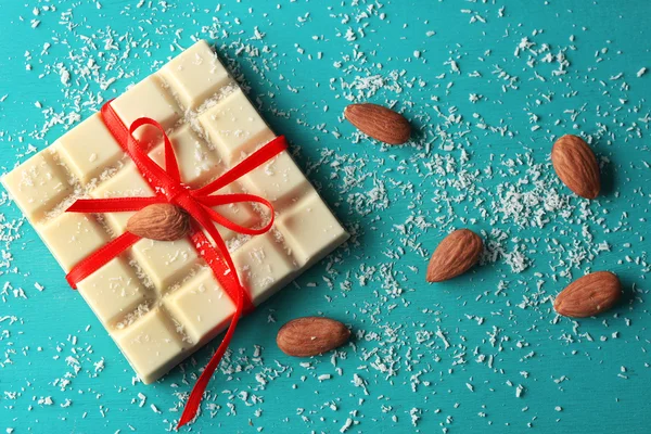 White chocolate bar with coconut shavings on color wooden background