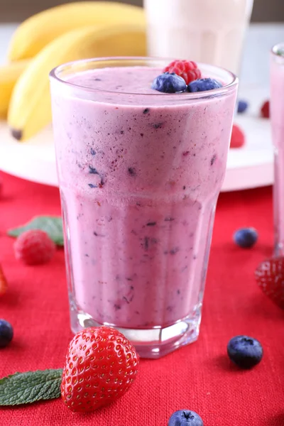 Milchshakes mit Beeren auf rotem Textil auf hellem Hintergrund — Stockfoto