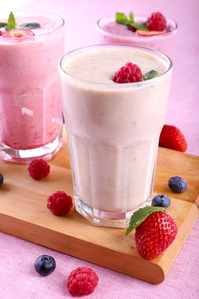 Milkshakes à la planche à découper avec des baies sur fond clair — Photo