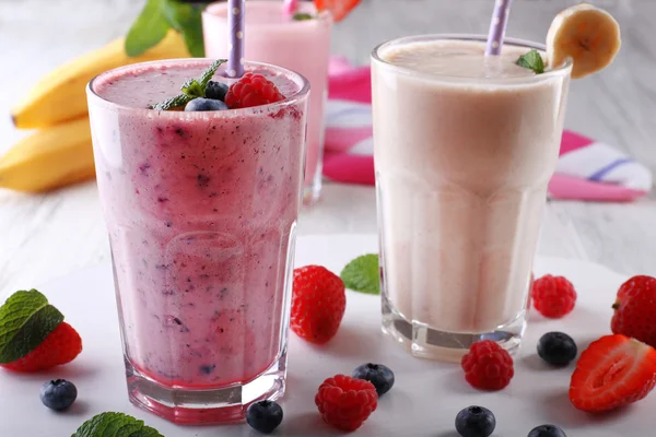 Milchshakes mit Beeren auf hellem Holzgrund, Nahaufnahme — Stockfoto