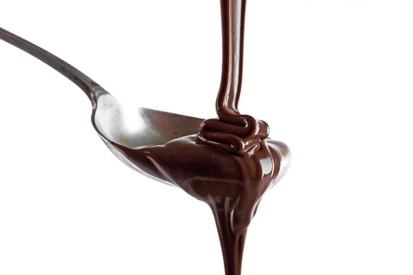 Melted milk chocolate pouring from a spoon, isolated on white — Stock Photo, Image