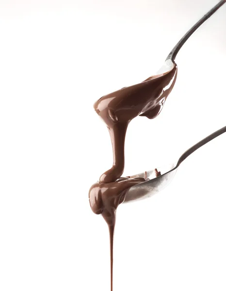 Растаянный молочный шоколад, наливающийся из ложек, изолированный на белом — стоковое фото