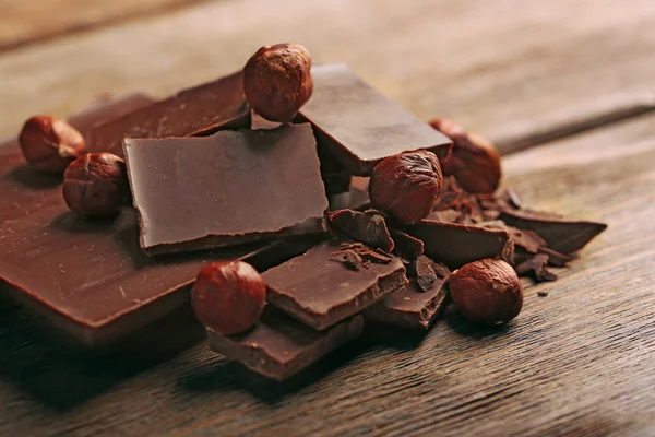 Svart choklad bitar med nötter på trä bakgrund — Stockfoto