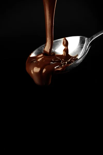 Chocolate poured on a spoon on dark background — Stock Photo, Image