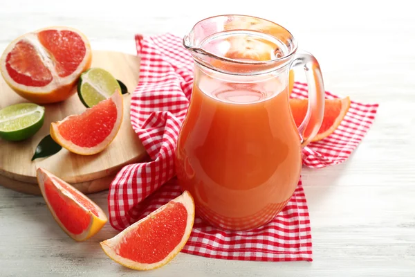 Jar of citrus juice and fresh fruits on light wooden background — Stock Photo, Image