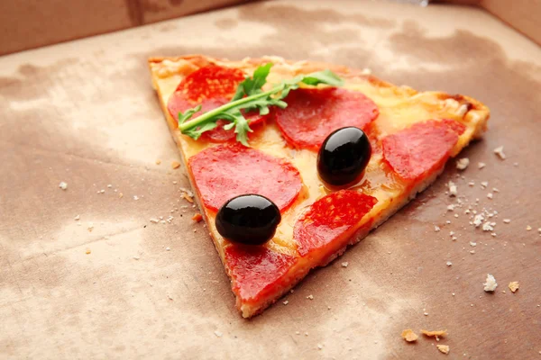 Plak van pepperoni pizza met rucola en olijven op karton — Stockfoto