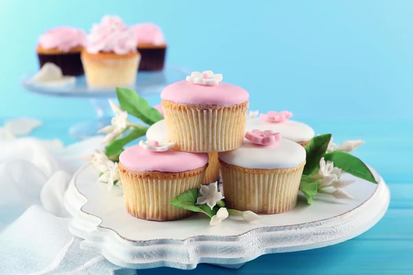 Smakelijke cupcakes op stand, op een houten achtergrond kleur — Stockfoto