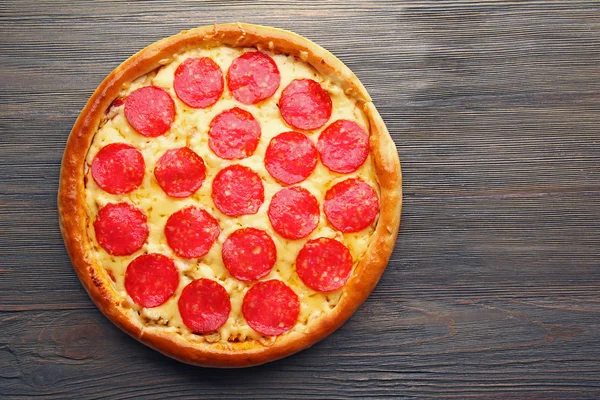 Ahşap arka planda salamlı lezzetli bir pizza. — Stok fotoğraf