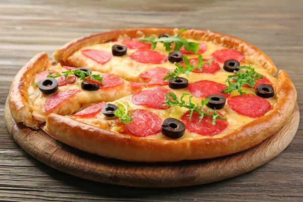 Pizza caliente sabrosa con salami y aceitunas sobre fondo de madera — Foto de Stock