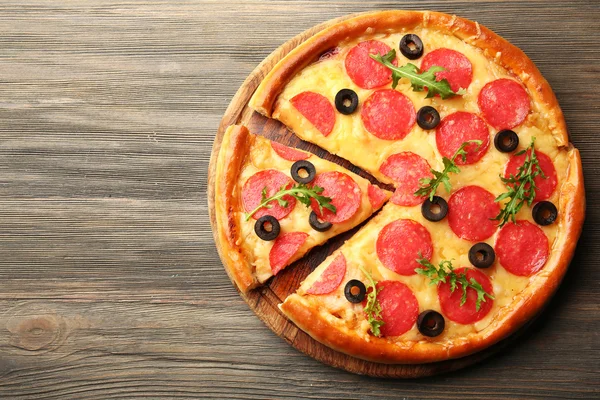 Pizza calda e gustosa con salumi e olive su fondo di legno — Foto Stock