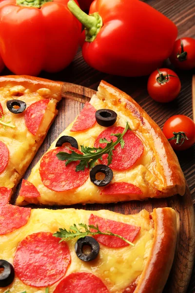 Pizza gostosa quente com salame e azeitonas em fundo de madeira, close-up — Fotografia de Stock