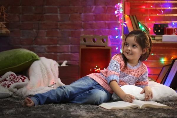 Jolie petite fille avec livre dans la chambre décorée de Noël — Photo