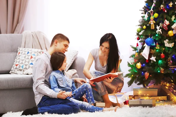 Glückliche Familie liest Buch im geschmückten Weihnachtszimmer — Stockfoto