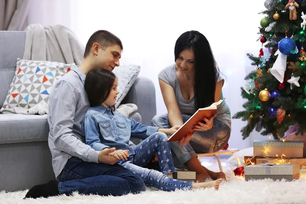 Glückliche Familie liest Buch im geschmückten Weihnachtszimmer — Stockfoto