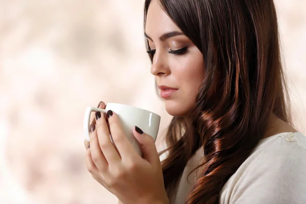 Ritratto di giovane bella donna con tazza di caffè su sfondo rosa sfocato, primo piano — Foto Stock