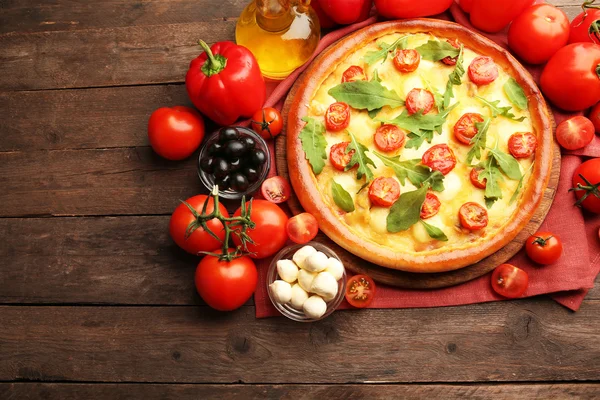 Pizza Margherita med rucola och grönsaker på träbord — Stockfoto