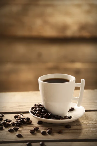 Tasse Kaffee und Kaffeekörner auf Holzgrund — Stockfoto