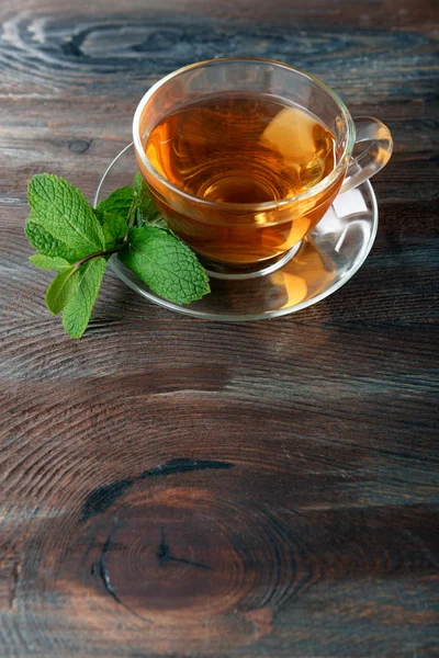 Glass cup of tea with mint leaves on wooden background — Stock Photo, Image
