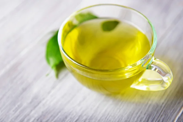 Taza de té con hojas verdes sobre fondo gris de madera — Foto de Stock