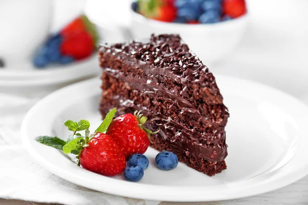 Schokoladenkuchen mit Schokoladencreme und frischen Beeren auf Teller, auf hellem Hintergrund — Stockfoto