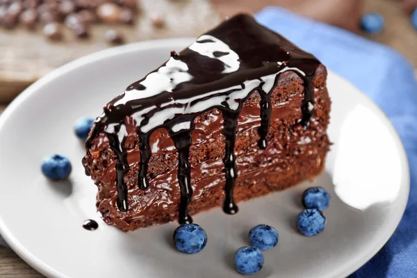 Pastel de chocolate con crema de chocolate y arándanos frescos en el plato, sobre fondo de madera — Foto de Stock