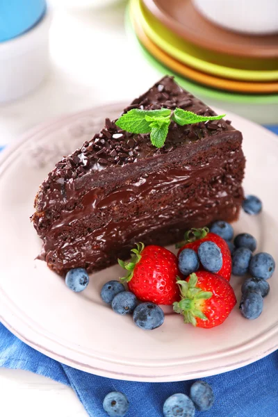 Pastel de chocolate con crema de chocolate y bayas frescas en el plato, sobre fondo de madera — Foto de Stock