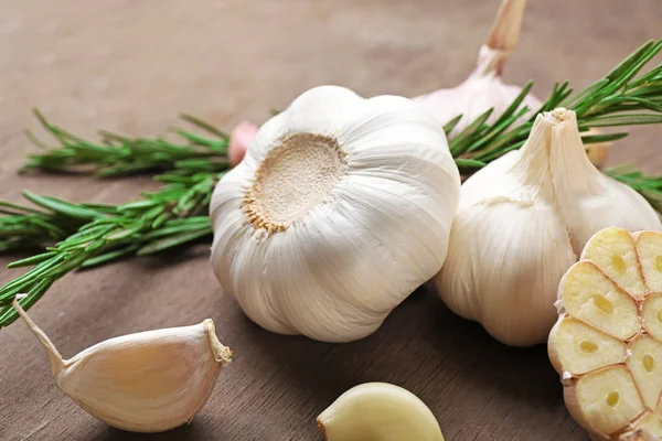 Komposition aus Knoblauch und Rosmarin auf Holzgrund, Nahaufnahme — Stockfoto