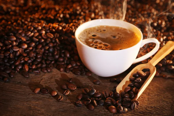 Чашка кави та кавових зерен на столі — стокове фото