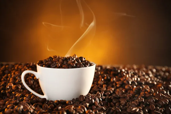 Kopp kaffe och kaffebönor på mörk bakgrund — Stockfoto