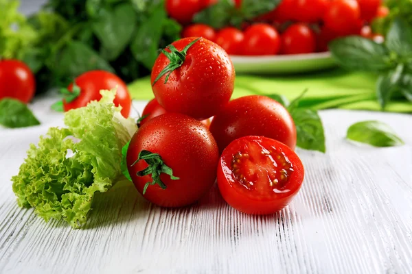 Pomodori ciliegini con basilico e lattuga sul tavolo di legno da vicino — Foto Stock