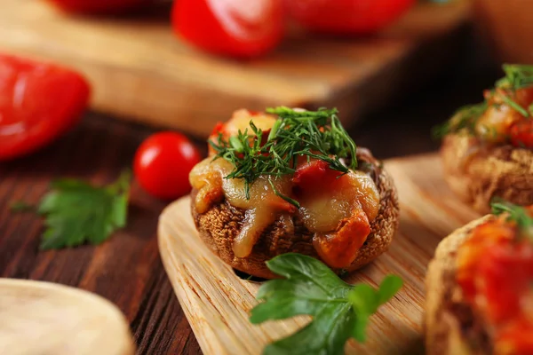 Une tablette en bois avec des champignons farcis et des légumes sur la table, gros plan — Photo