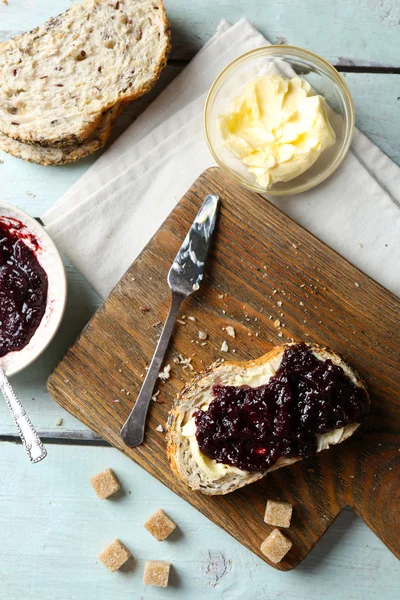 Heerlijke jam in de kom, boter, vers brood en crackers op blauwe houten achtergrond — Stockfoto